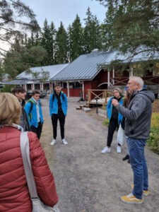 ravintolan pihalla ryhmä kokoontunut mies henkilön ympärille, joka kertoo asiaa