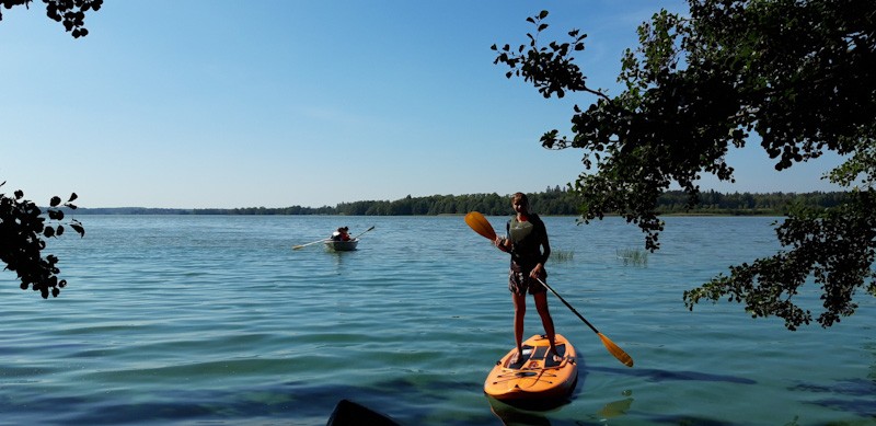 Henkilö suppilaudan päällä järvellä. 